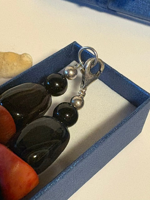 Karabinerverschluss aus silberfarbenem Metall an einer Vintage-Korallenkette mit Onyx.