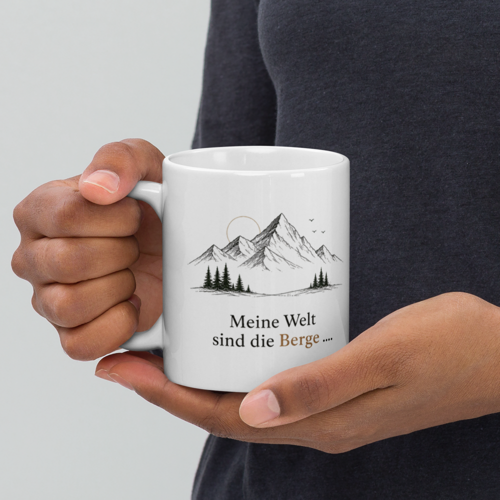 Hand hält weiße Tasse mit Berglandschaft und deutschem Spruch vor dunklem Hintergrund