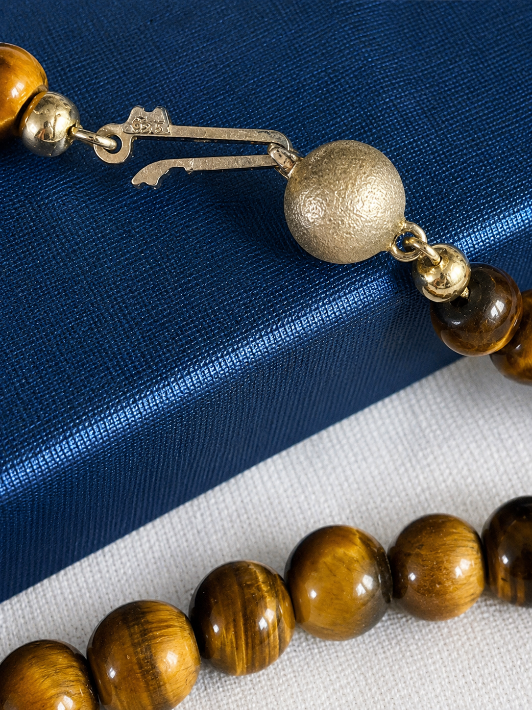 Detailaufnahme des 925 Silberverschlusses einer Vintage Tigerauge Halskette aus echtem Tigerauge. Natürlicher Natursteinschmuck mit goldbraunen Tigerauge-Perlen.