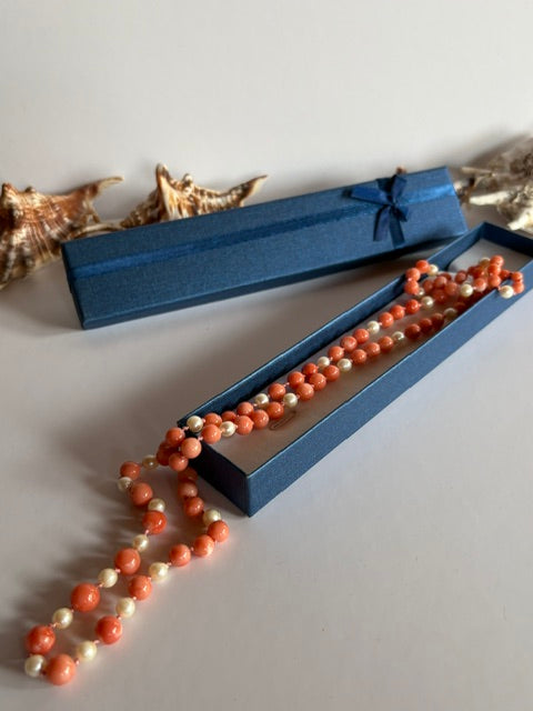 Lange Vintage-Korallenkette mit Zuchtperlen neben blauer Schmuckschachtel