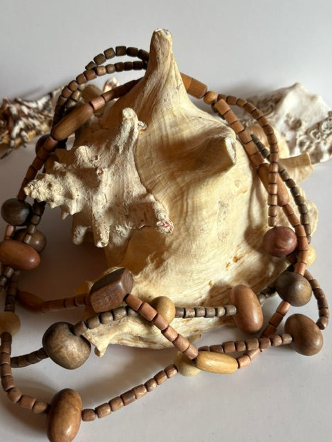 Dreireihige Boho-Holzkette mit unterschiedlich geformten Vintage-Perlen dekoriert auf einer großen Muschel