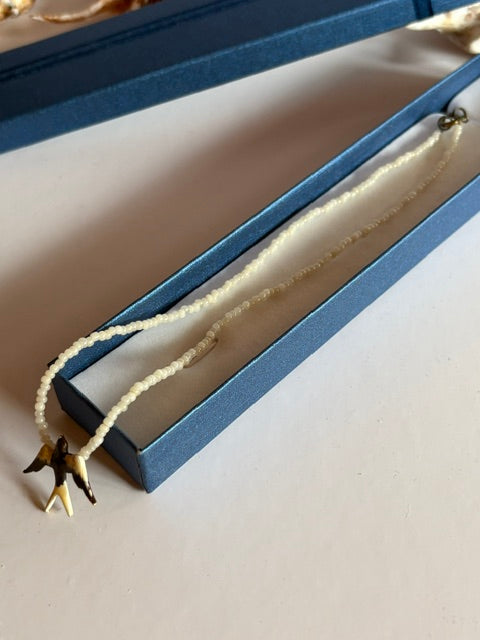 Kurze Vintage-Perlenkette mit Vogelanhänger in einer blauen Schmuckschachtel