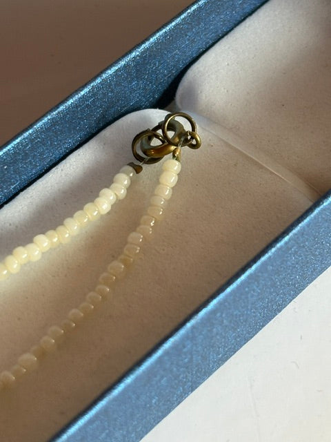 Detail des goldfarbenen Ringverschlusses an der cremefarbenen Vintage-Perlenkette