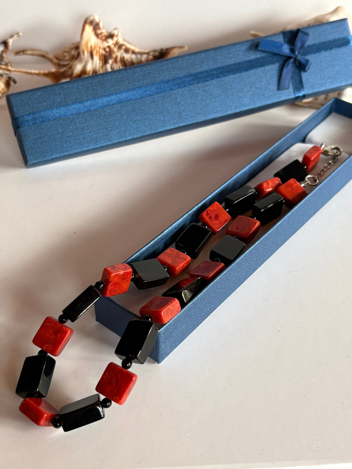Vintage Koralle-Onyx-Kette neben einer blauen Schmuckschachtel
