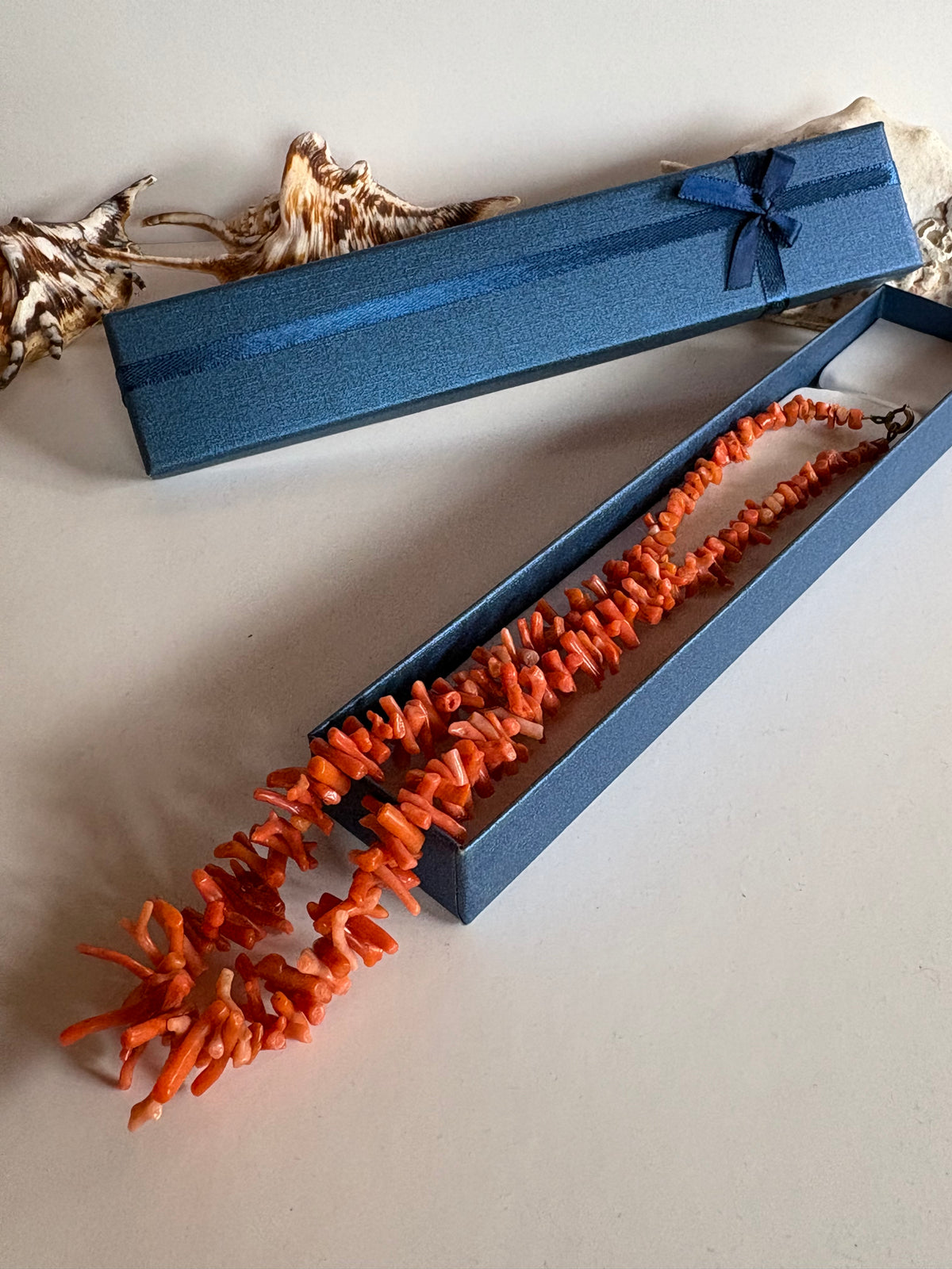 Vintage Korallenkette aus Astkoralle neben einer blauen Schmuckschachtel