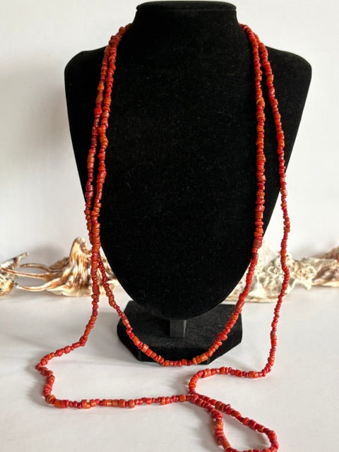 Lange Vintage-Korallenkette in Rot-Orange mit kleinen unregelmäßigen Perlen auf einer schwarzen Schmuckbüste