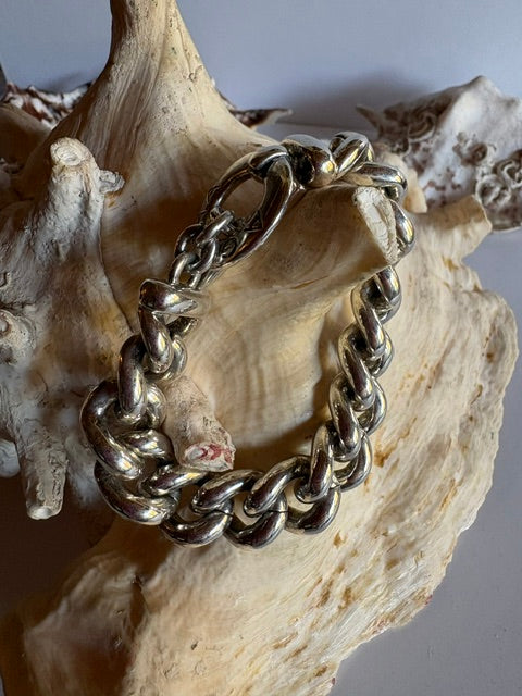 Silberfarbenes AGATHA Panzerarmband mit großen, gerundeten Kettengliedern, auf einer Muschel dekoriert.