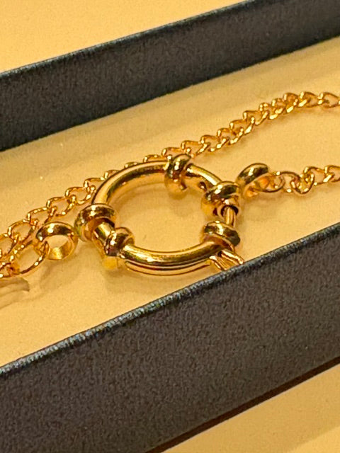 Close-up of the large gold-tone spring ring clasp and chain links on a handmade cowrie shell necklace by Frau Muschel.