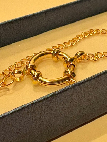 Close-up of the large gold-tone spring ring clasp and chain links on a handmade cowrie shell necklace by Frau Muschel.