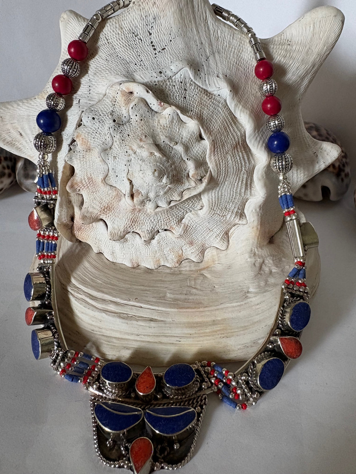 Ethno-inspiriertes Vintage-Collier mit blauen und roten Steinen auf großer Muschel