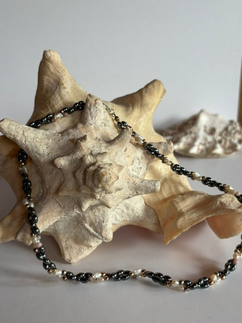 Vintage-Kette mit Hämatit, cremefarbenen Perlen und goldfarbenen Akzenten vor Muschel