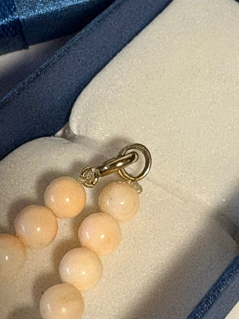 Nahaufnahme des goldfarbenen Karabinerverschlusses einer cremeweißen Vintage-Korallenkette