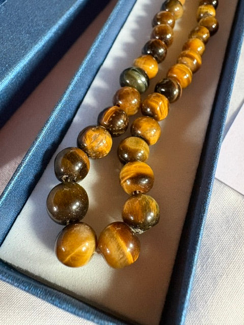 Detailansicht einer Vintage Tigerauge Halskette aus echtem Tigerauge. Natürliche goldbraune Tigerauge-Perlen mit charakteristischem Schimmer in einer Schmuckschatulle.