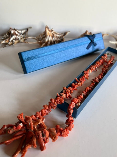 Rotorangefarbene Vintage-Korallenkette S206 über einer geöffneten blauen Schmuckschachtel
