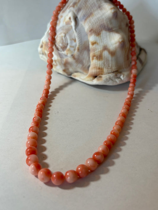 Rosa Vintage-Korallenkette mit harmonisch abgestuften Kugelperlen auf einer Muschel drapiert.