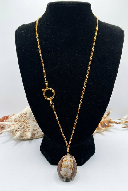 Handmade gold-tone cowrie shell necklace with asymmetrical design and large spring ring clasp displayed on a black jewelry bust.