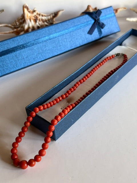 Vintage-Korallenkette mit Perlen im Größenverlauf über einer offenen blauen Schmuckschachtel