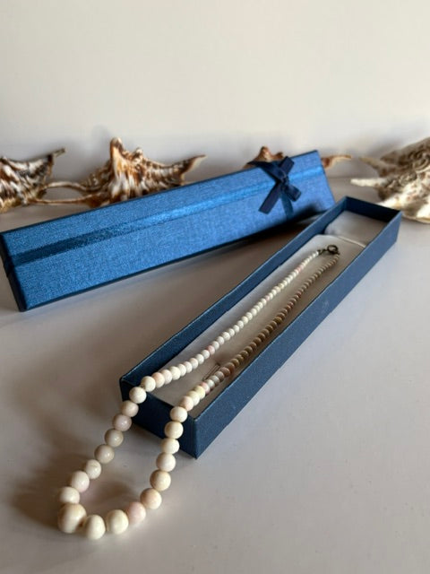 Vintage-Korallenkette mit hellen Perlen im Größenverlauf über einer offenen blauen Schmuckschachtel