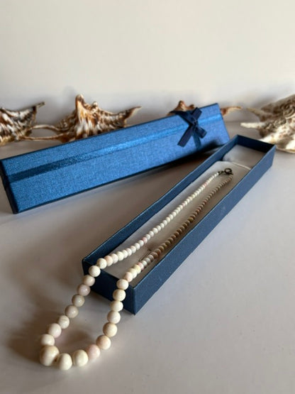 Vintage-Korallenkette mit hellen Perlen im Größenverlauf über einer offenen blauen Schmuckschachtel