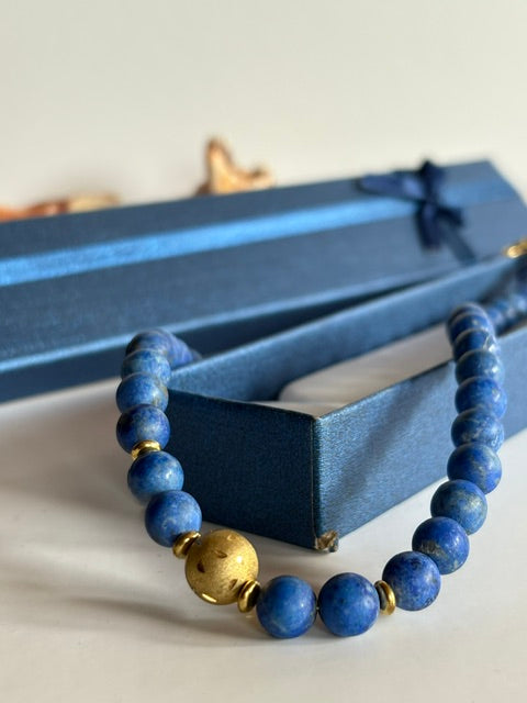 Goldfarbene Mittelkugel und blaue Lapislazuli-Perlen in Nahaufnahme