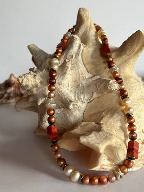 Vintage-Kette mit Perlen, Perlmutt und Schaumkoralle dekorativ auf einer großen Muschel