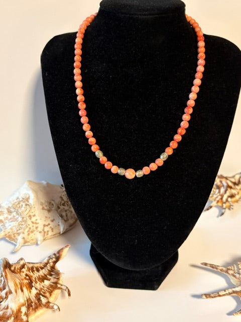 Roséfarbene Vintage Korallenkette mit dekorativen Metallperlen auf schwarzer Schmuckbüste