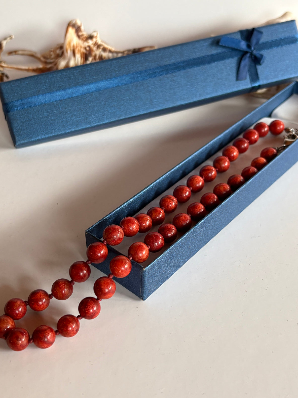 Rote Korallenkette als maritimer Vintage-Schmuck neben einer blauen Schmuckschachtel